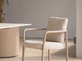 eleganter Outdoor Sessel in einem Naturton und hellen komfortablen Kissen.