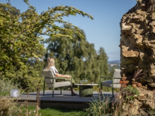eleganter Loungesessel in gr&uuml;n mit grauen Kissen in der Natur
